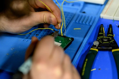 Nick Scaperdas, who studies bioengineering, solders electrical wires together on a keypad for a doorbell in the Sherman Center in Hayden Hall on Feb. 28, 2023.